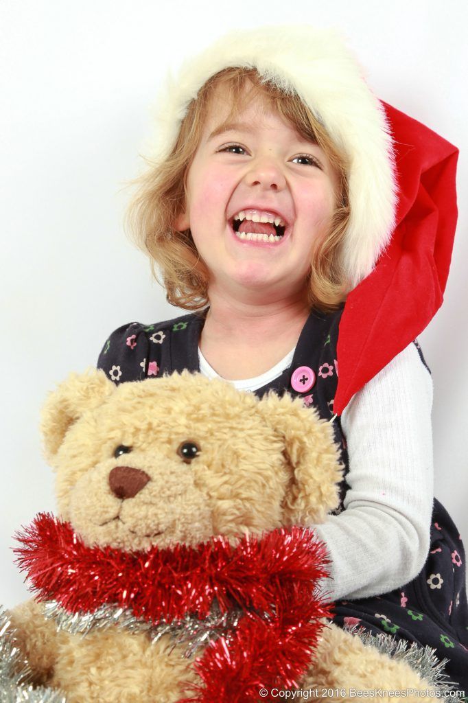 a girl and her teddy wearing tinsel and a santa hat