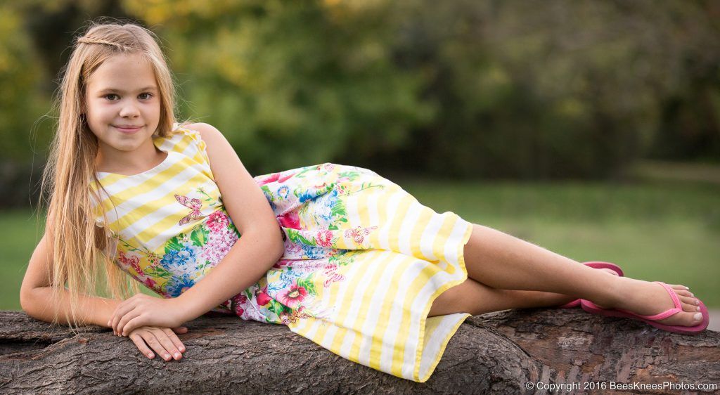 a young girl lying on a fallen tree in the park