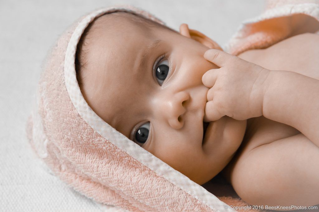 baby sucking fingers looking cute wrapped in a towel