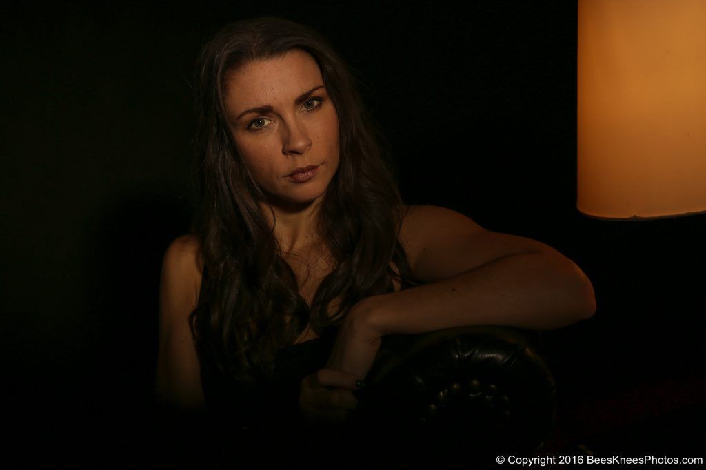 dark indoor portrait of a woman and a lamp