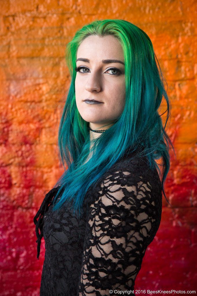 green haired woman in front of an orange wall