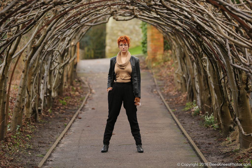 lady standing in an archway of plants