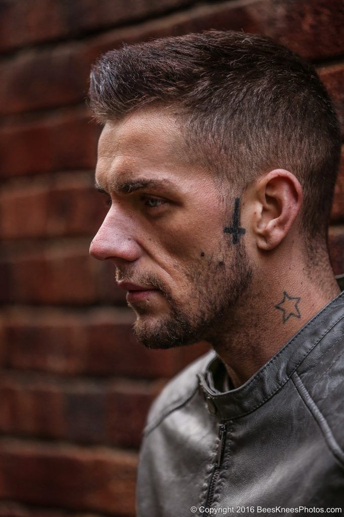 man standing against a brick wall