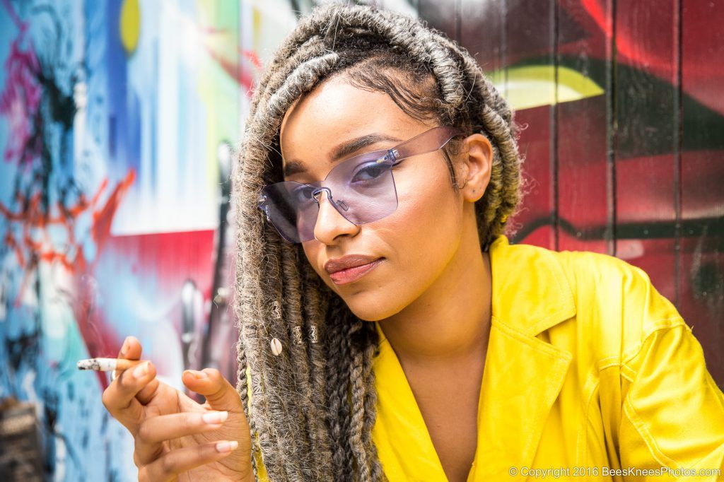 urban portrait of a woman in yellow smoking