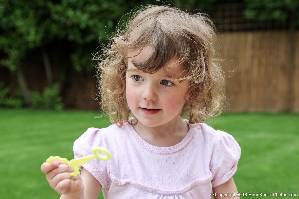 young girl blowing bubbles in the garden
