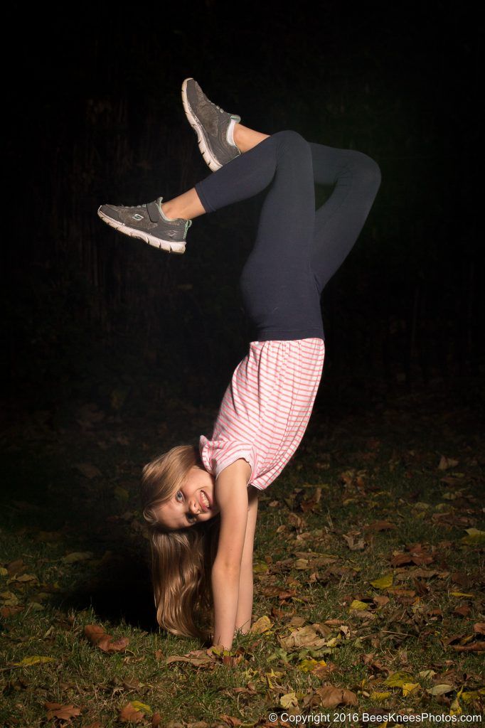 young girl doing a handstand in the park at night