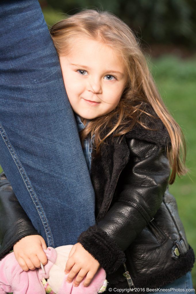 young girl holding onto her dads leg
