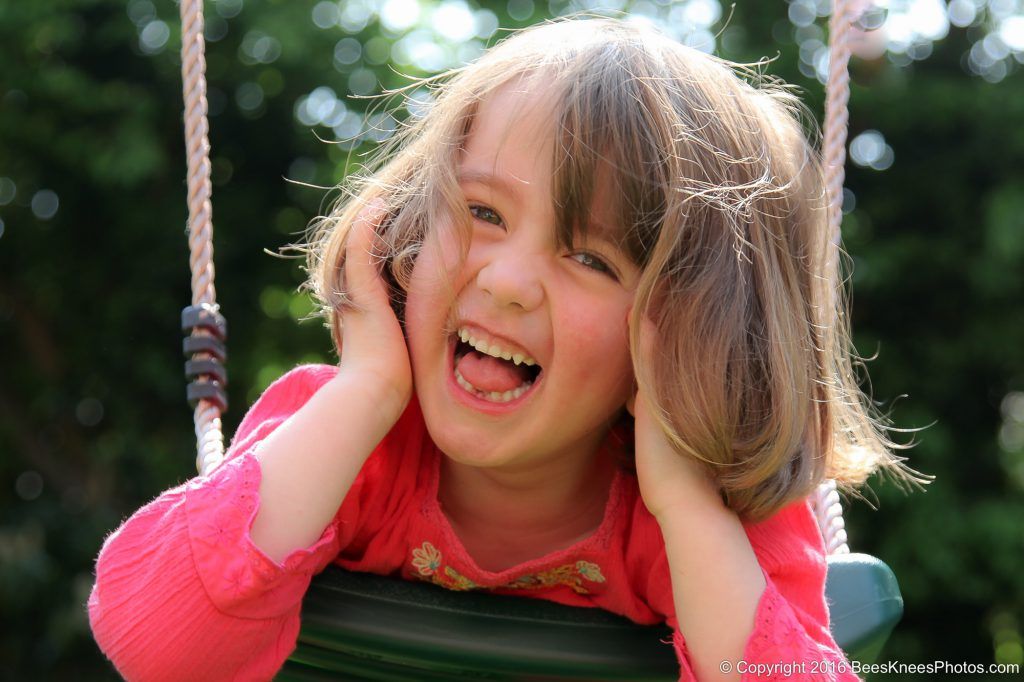 young girl laughing on a swing